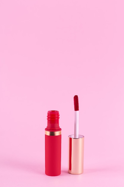 Rossetto e bacchetta applicatore su sfondo rosa pastello Stick per labbra liquido rossetto per lucidalabbra tubo aperto