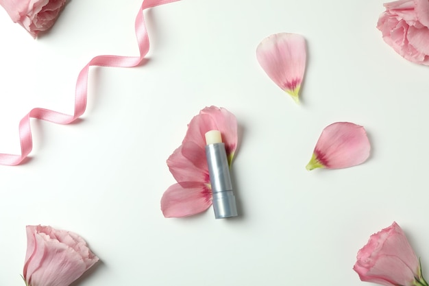 Rossetto igienico e rose su sfondo bianco