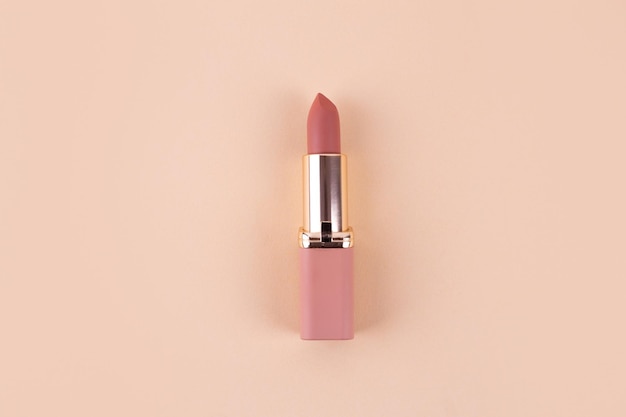 Rossetto opaco nude su fondo beige in tubo piatto rosa e oro Prodotto cosmetico professionale
