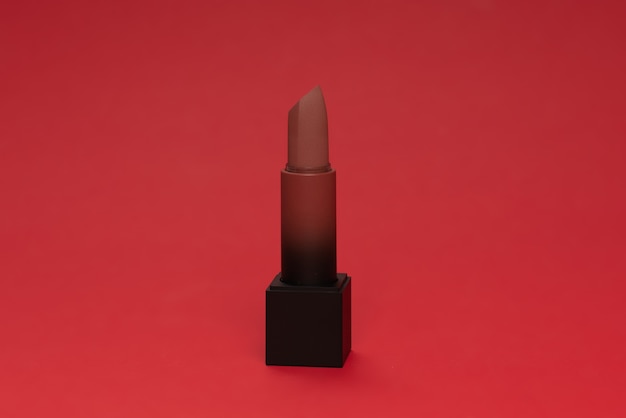 Rossetto rosso su una superficie rossa. Trucco per le donne.