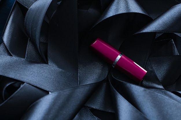 Rossetto viola su sfondo di seta nera trucco di lusso e cosmetici di bellezza