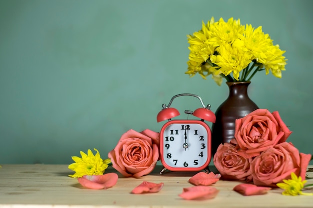 Rosso allarme, rosa, fiore giallo crisantemo in vaso su legno a mezzogiorno.