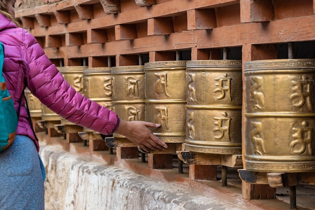 Rotelle di preghiera buddisti tibetane di filatura della mano della donna, India.