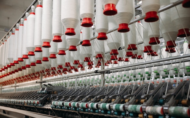 Rotoli bianchi di filo di cotone industriale per la produzione di indumenti tessili su una macchina.