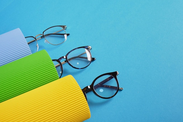 Rotoli di cartone ondulato e diverse paia di eleganti montature per occhiali da vista nella tendenza della moda