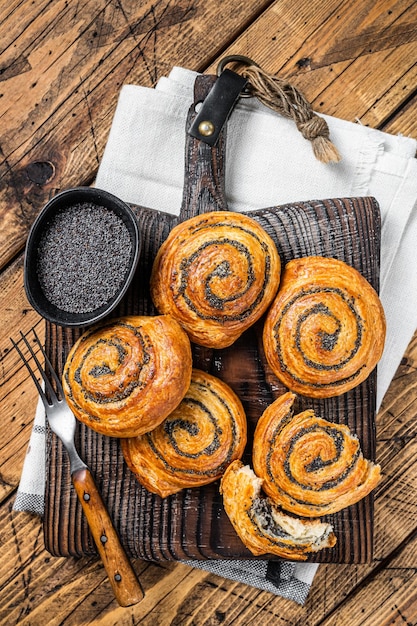 Rotoli di semi di papavero e panini di cardamomo Tradizionale pane dolce nordico cotto su tavola di legno Sfondio in legno Vista superiore