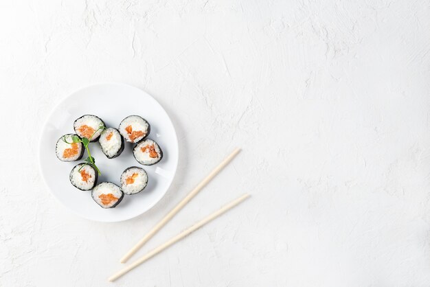 Rotoli di sushi a forma di cuore con le bacchette su un piatto bianco. San Valentino.