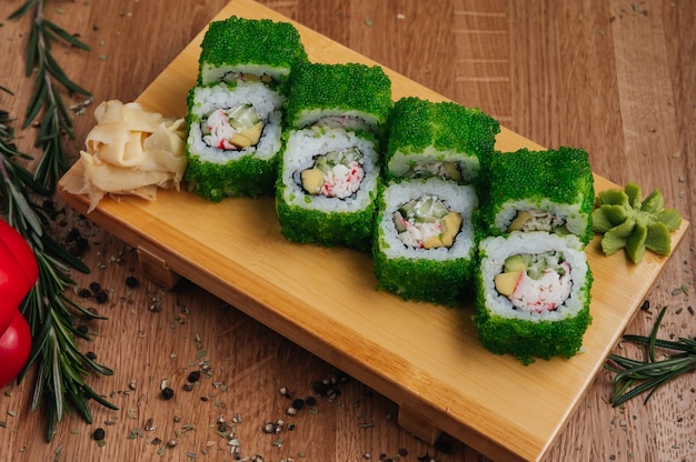 Rotoli di sushi con caviale verde Tobiko su tavola di legno