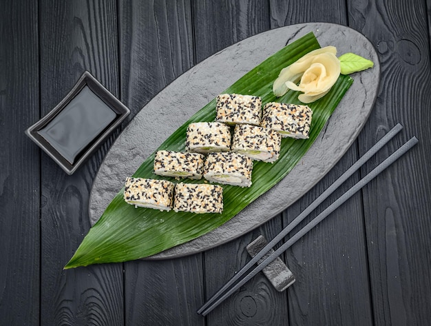Rotoli di sushi con gamberetti e sesamo Rotolo di sushi fresco e delizioso tradizionale su sfondo nero Menu di sushi Ristorante di cucina giapponese Cibo asiatico