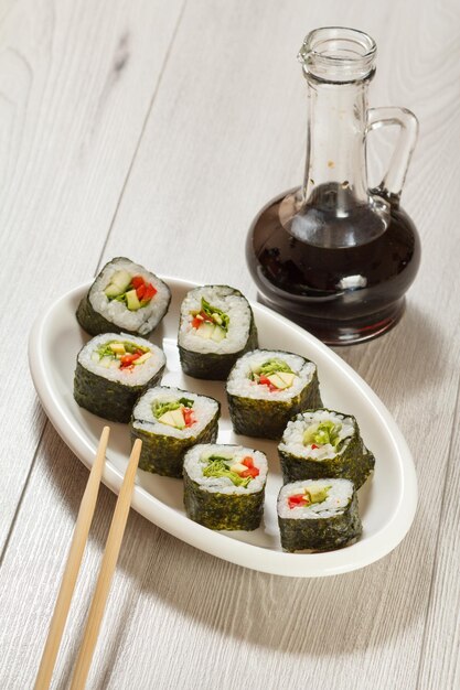 Rotoli di sushi con pezzi di riso di avocado, cetriolo, peperone rosso e foglie di lattuga