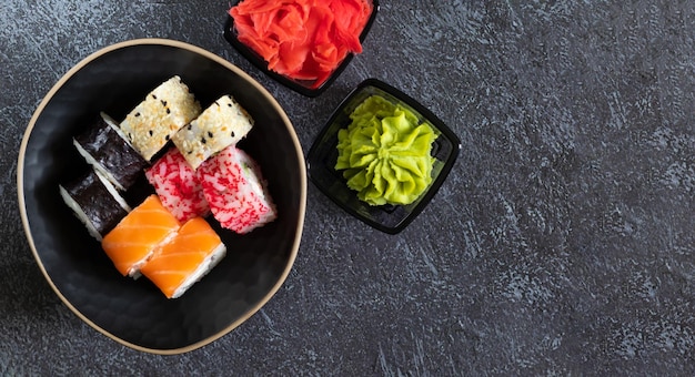Rotoli di sushi con zenzero wasabi su sfondo scuro con spazio per la copia a destra