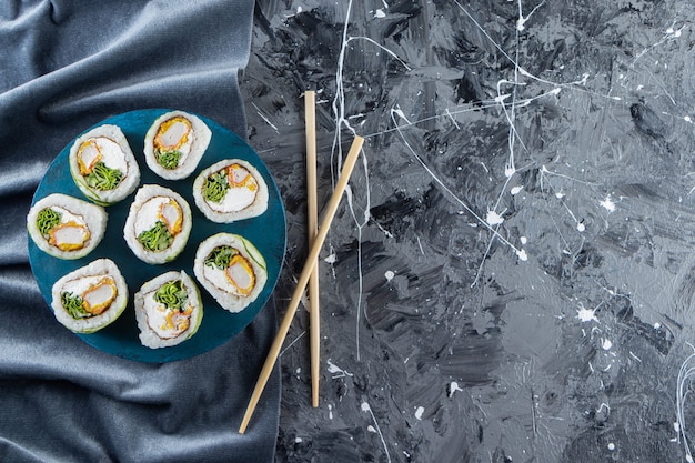 Rotoli di sushi del drago verde disposti sul bordo blu.