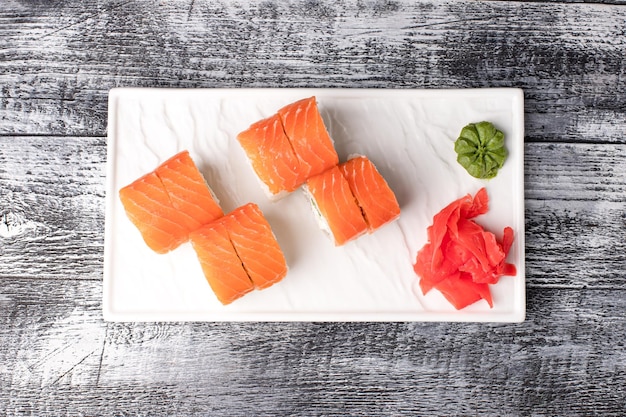 Rotoli di sushi di sushi con pesce su uno sfondo bianco di legno