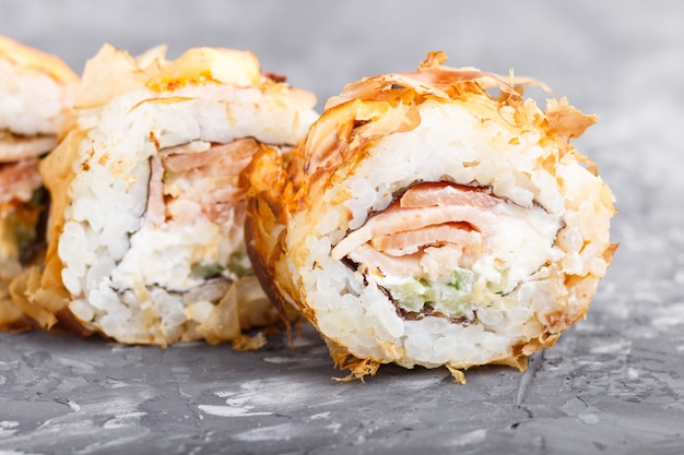 Rotoli di sushi giapponesi di maki con il formaggio del cetriolo di tonno su fondo concreto nero