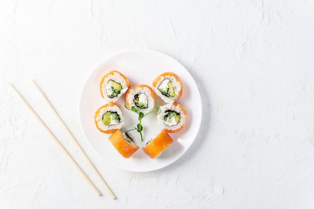 Rotoli di sushi per San Valentino sotto forma di un cuore su un piatto bianco.