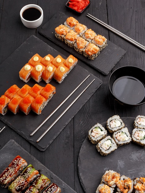 Rotoli di sushi su piatti colorati su uno sfondo nero