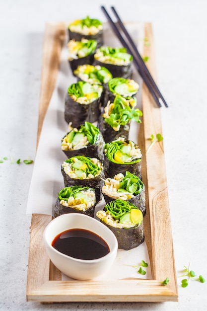 Rotoli di sushi vegan verde su una tavola di legno.