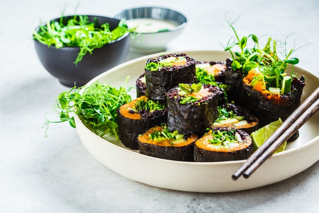 Rotoli di sushi vegani con riso nero, avocado e patata dolce sul piatto bianco