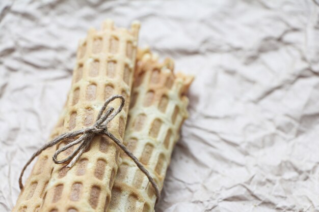 Rotoli di wafer fatti in casa legati con iuta su carta da forno stropicciata.