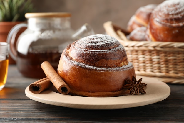 Rotoli, tè e pianta di cannella sulla tavola di legno