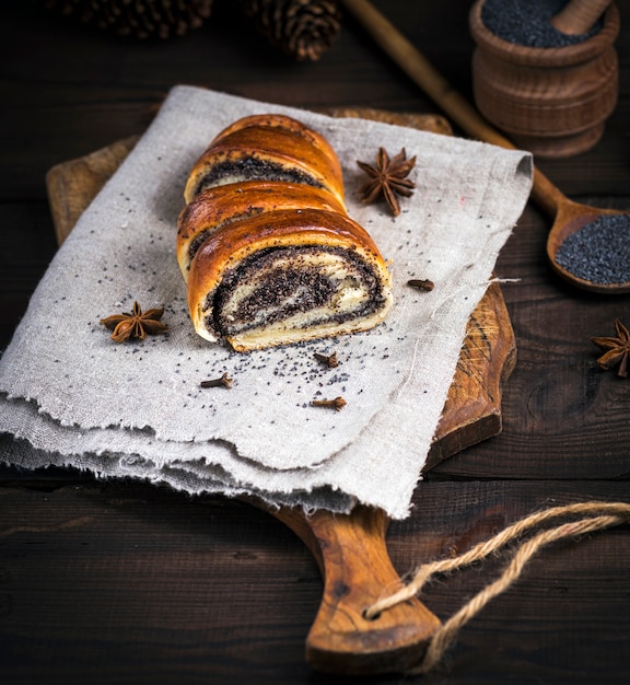 Rotolo al forno con semi di papavero su una tavola di legno marrone