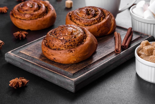 Rotolo alla cannella appena sfornato con spezie e ripieno di cacao su fondo nero