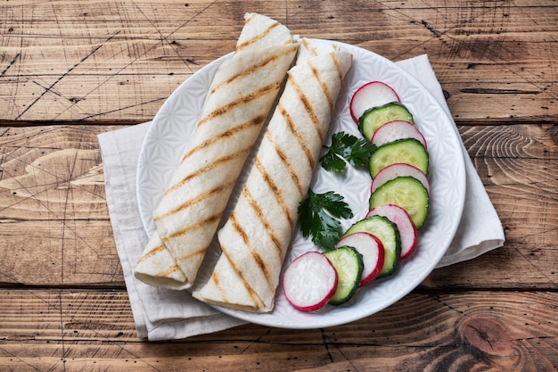 Rotolo con formaggio ed erbe. Pita alla griglia con ripieno. Insalata di ravanello di cetriolo. Il concetto di una sana colazione.