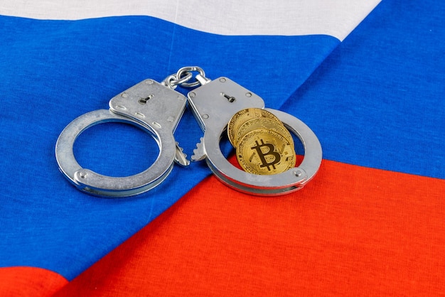 Rotolo di carta russa rubli valuta e bitcoin shiner incatenato con manette su sfondo bandiera russa