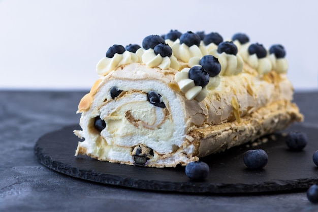 Rotolo di meringa su sfondo scuro Delizioso dessert con i mirtilli