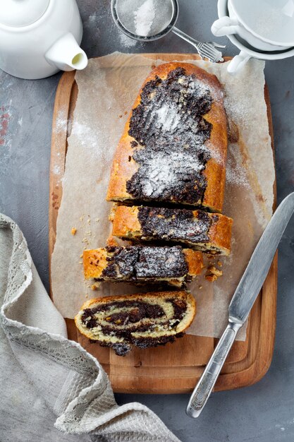 Rotolo di miele con semi di papavero e uvetta su una superficie di cemento grigio. Messa a fuoco selettiva Vista dall'alto.