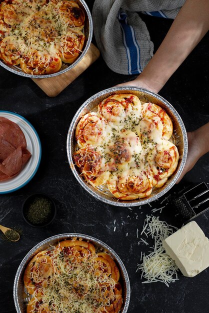 Rotolo di pizza con topping di formaggio fuso su una teglia rotonda in alluminio