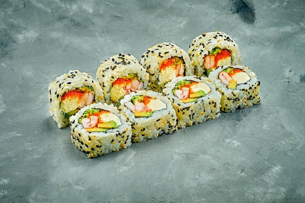 Rotolo di sushi al sesamo con gamberi e formaggio avocado su sfondo grigio Rumore aggiunto in postproduzione