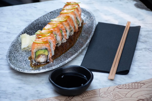 rotolo di sushi maki con salmone avocado e gamberetti tritati e bacchette