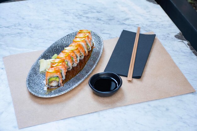 rotolo di sushi maki di salmone, avocado e gamberetti tagliati e bacchette angolate