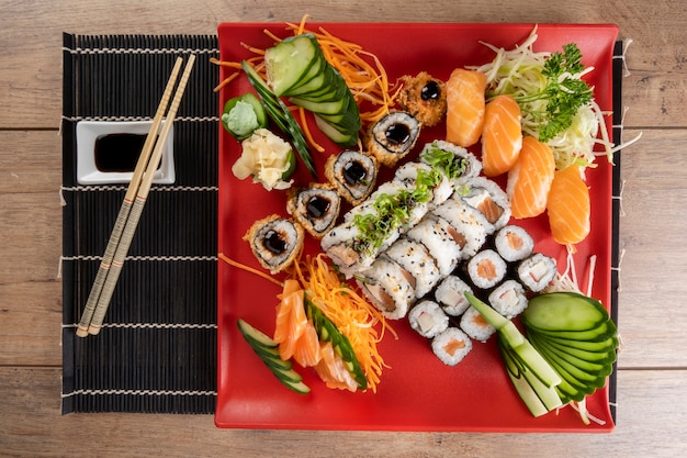 Rotolo di sushi misto e sashimi di salmone sul piatto rosso