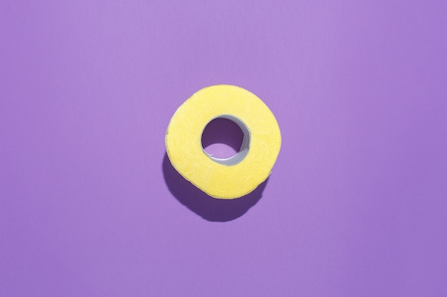 Rotolo giallo di carta igienica su uno sfondo viola.