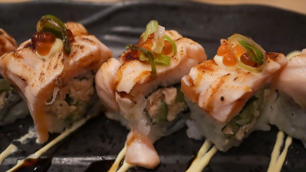 Rotolo piccante di salmone Oyako composto da pelle di salmone croccante avvolta da riso sushi condito con salmone Aburi mezzo cotto alla griglia con salsa piccante