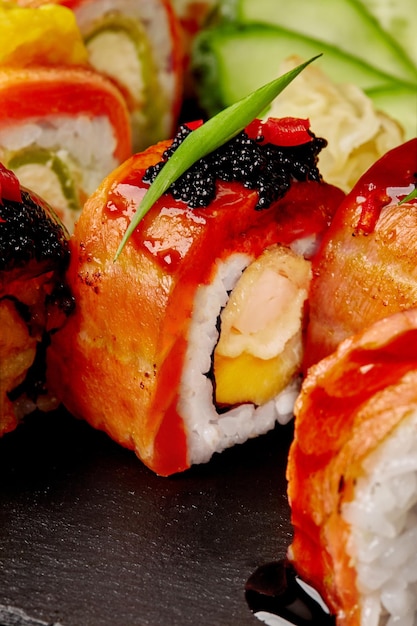 Rotolo Uramaki con gamberi mango salmone tobiko nero e salsa unagi con sushi assortito