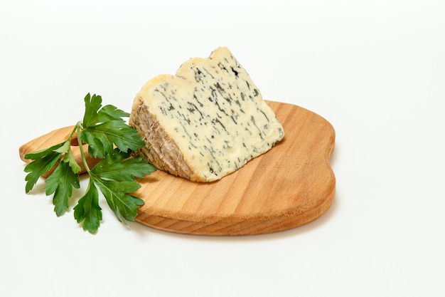 Rottura di Fourme d'Ambert, un formaggio blu francese semiduro e prezzemolo fresco su un tagliere di legno con la superficie bianca