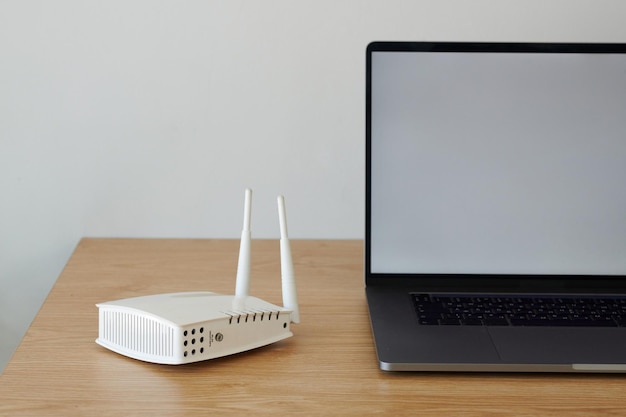 Router Wi-Fi accanto al laptop aperto sulla scrivania in legno