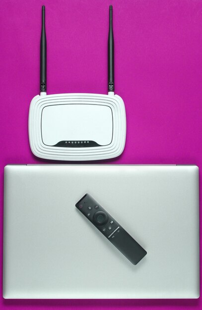 Router Wi-Fi, laptop, mouse per pc, telecomando su sfondo rosa