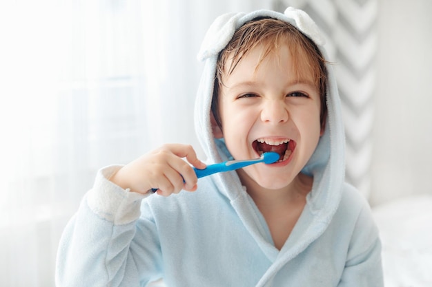 Routine mattutina sorridente bambino felice lavarsi i denti con spazzolino da denti Igiene dentale delle cure mediche del ragazzino