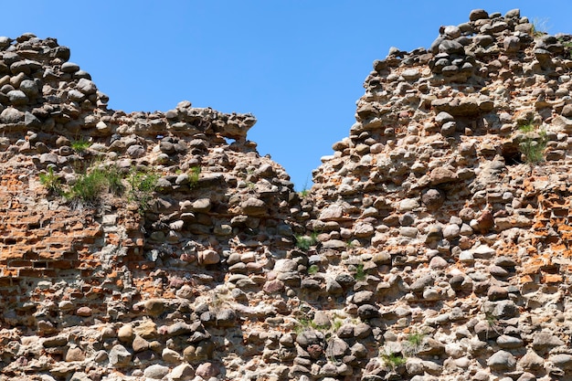 Rovinato e ricoperto di erba ruderi di un'antica fortezza e pietre e mattoni, ruderi di strutture difensive del medioevo