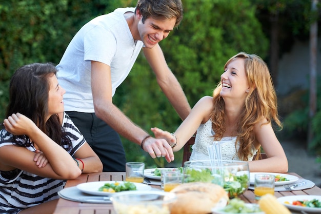 Rubare un piccolo pezzo Sorridente giovani a pranzo con un gruppo di amici ritratto