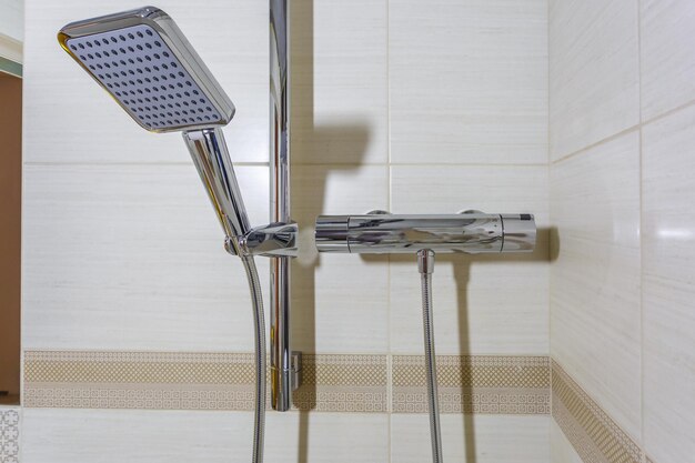 Rubinetto quadrato con rubinetto in bagno costoso dettaglio di una cabina doccia ad angolo con attacco doccia a parete