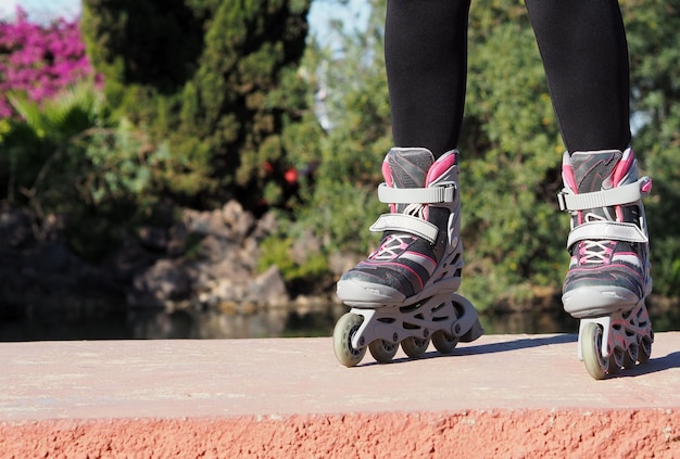 Rulli pattini in linea sui piedi femminili sullo sfondo del parco Primo piano