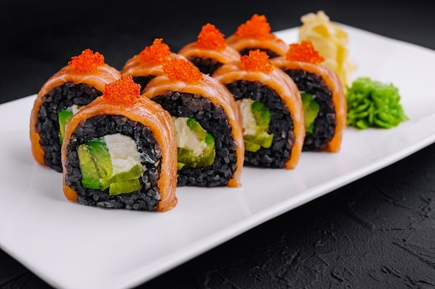 Rullini di sushi di riso nero con salmone su piatto bianco