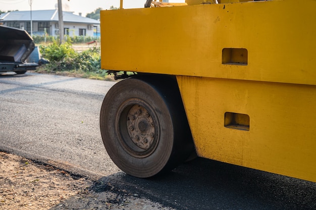 Rullo a vapore giallo a vibrazione pesante o compattatore del suolo che lavora su una pavimentazione in asfalto a caldo in cantiere