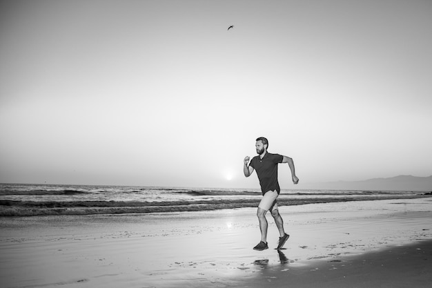 Runner uomo sulla spiaggia in esecuzione per l'esercizio Corridore sano attivo jogging all'aperto Giovane uomo trai