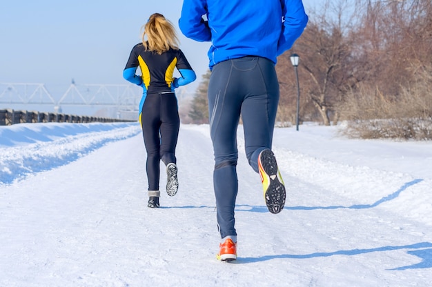Runners. Gambe, vista posteriore. Giovani coppie in esecuzione. Sport uomo e donna jogging su winter park